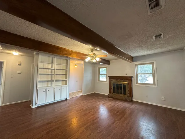 an empty room with windows fireplace and wooden floor