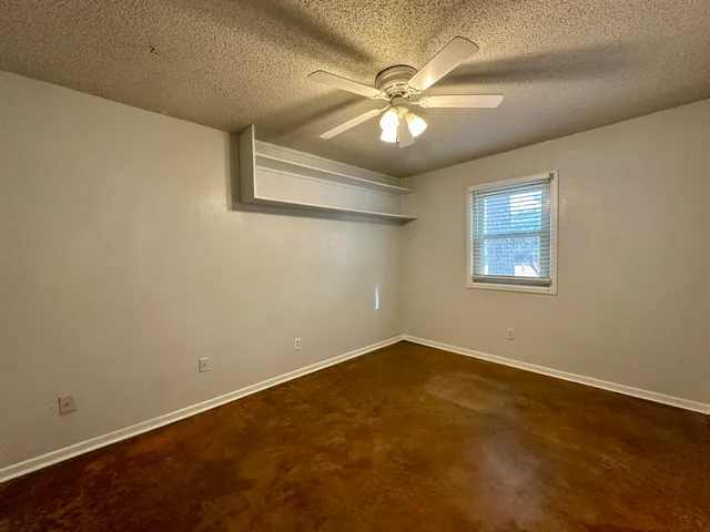 an empty room with a window and a fan