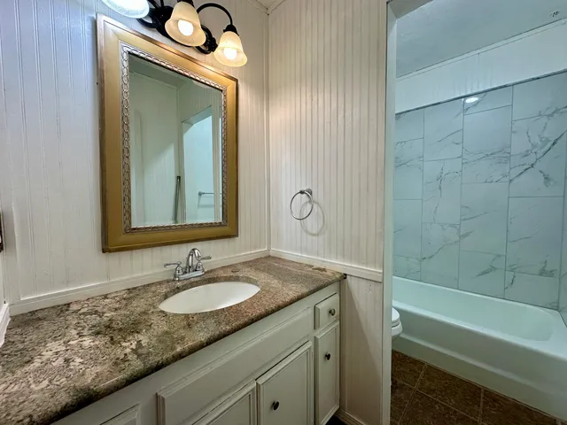 a bathroom with a granite countertop sink and a mirror