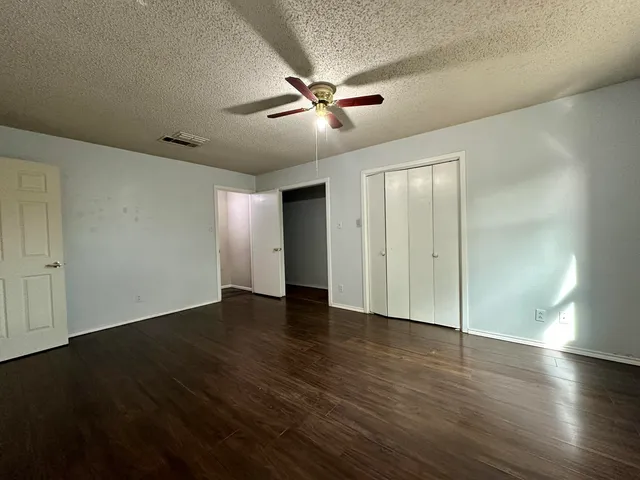 an empty room with wooden floor fan and windows