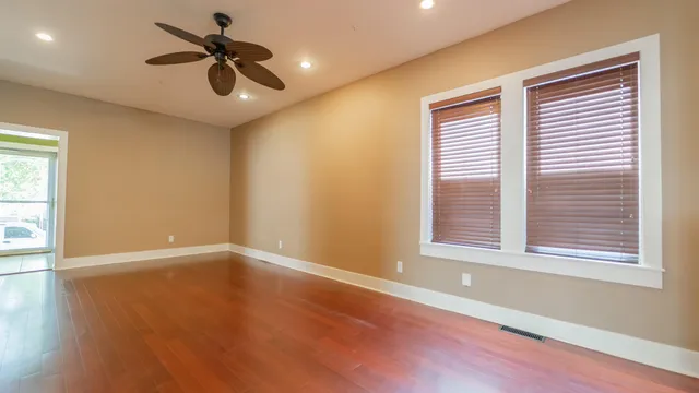 a view of an empty room with a window and wooden floor