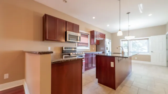 a kitchen with stainless steel appliances granite countertop wooden cabinets a stove top oven a sink and dishwasher