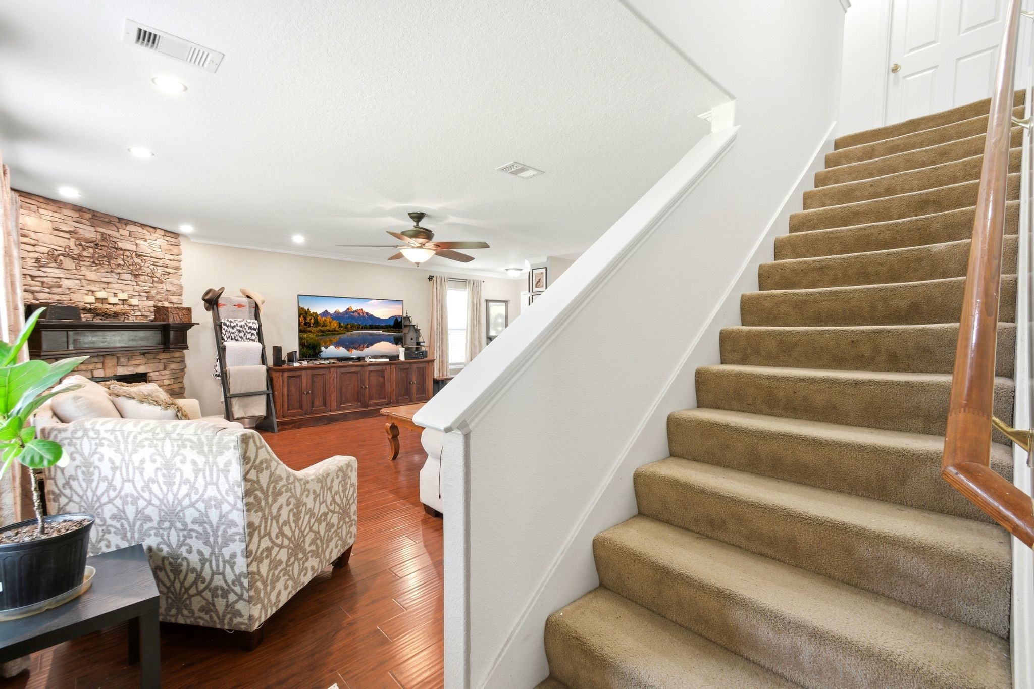 16954 Tableland Trail Conroe, TX 77385 - Photo 18 of 33 Open-concept living area featuring beautiful wood-look flooring, a striking stone fireplace, recessed lighting, and an elegant staircase leading to the second level. Designed for comfortable living and effortless entertaining.