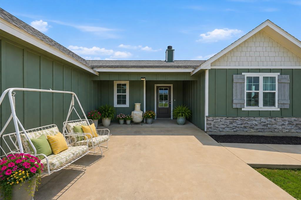 Virtually Staged Board and batten siding with stone accents, a covered entry, an exterior lighting fixture, and a glass-paneled entry door