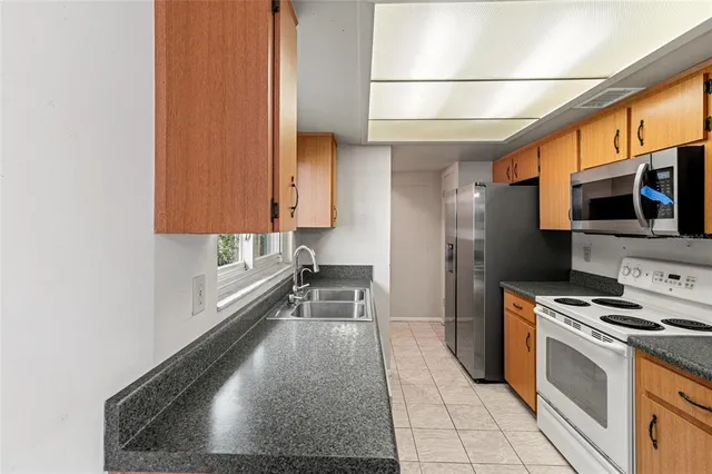 a kitchen with stainless steel appliances a sink a stove a microwave a counter space and cabinets