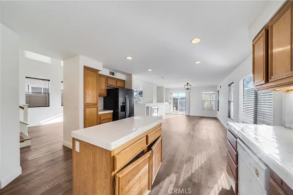 a view of a kitchen with kitchen island a refrigerator a sink dishwasher with wooden cabinets and floor to ceiling window