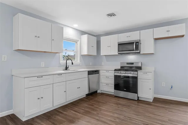 a view of an empty room with window and wooden floor