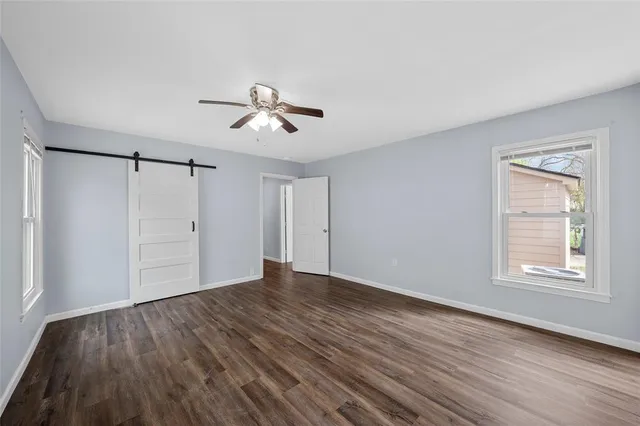 a view of an empty room with wooden floor fireplace and a window