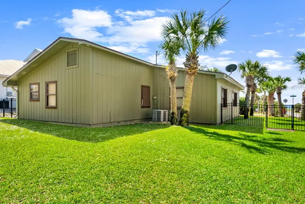 a yellow house with a big yard plants and large trees