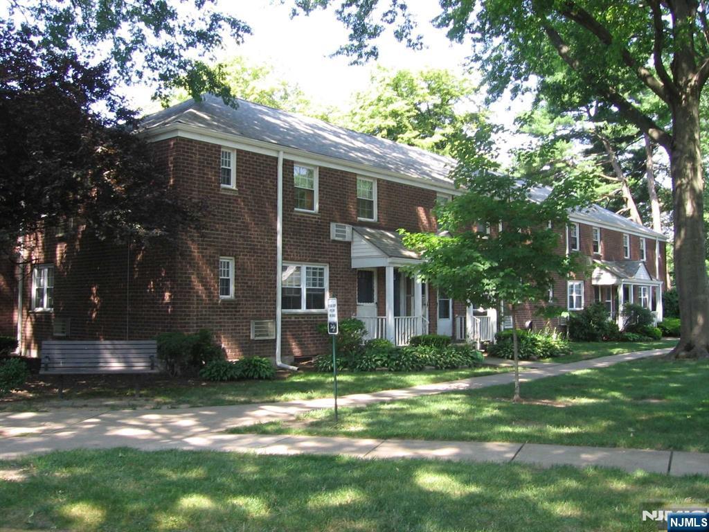 a view of a yard in front of a brick house with large windows