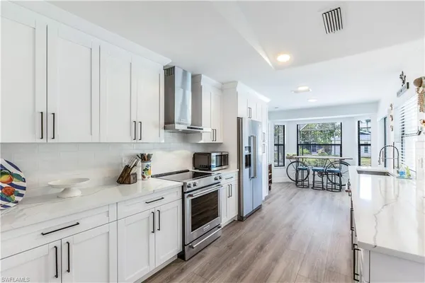 a kitchen with stainless steel appliances a white stove top oven cabinets and a wooden floor