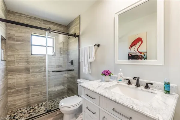 a bathroom with a granite countertop sink a toilet and shower