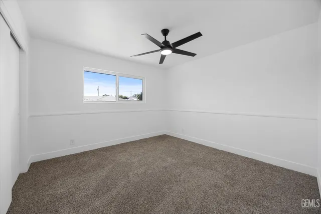 an empty room with a ceiling fan and window