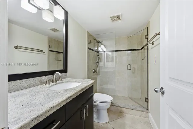a bathroom with a granite countertop sink toilet mirror and shower