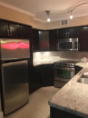 a kitchen with stainless steel appliances kitchen island granite countertop a refrigerator and a stove