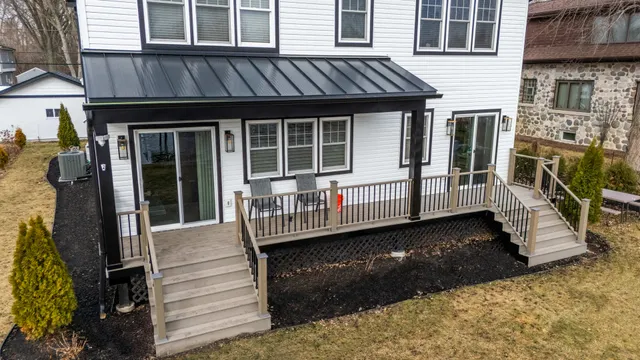 a view of a house with a wooden deck and furniture