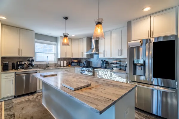 a kitchen with stainless steel appliances granite countertop a sink a stove a refrigerator cabinets and a kitchen island