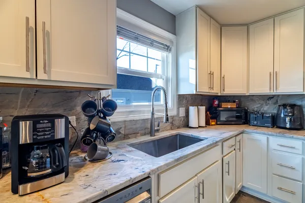 a kitchen with granite countertop a sink a counter top space and cabinets