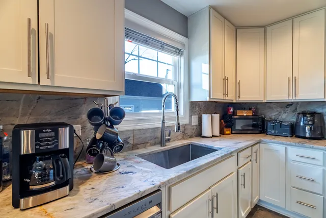 a kitchen with granite countertop a sink a counter top space and cabinets