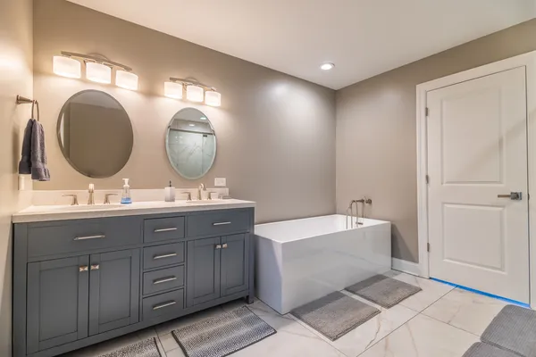 a bathroom with a double vanity sink mirror and bathtub
