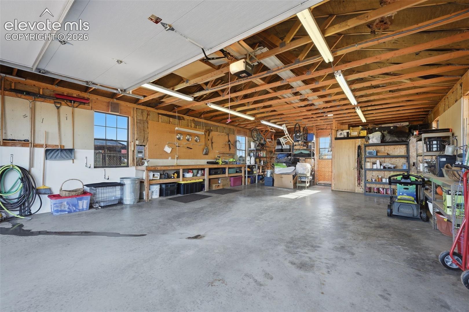 6015 West Condor Road Peyton, CO 80831 - Photo 50 of 50 Spacious garage with exposed wood beam ceiling, concrete flooring, and multiple windows