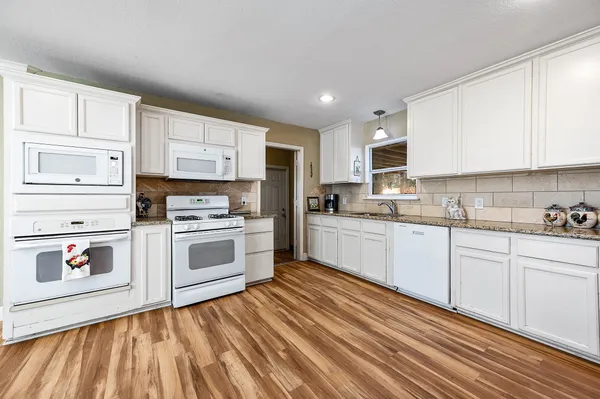 a kitchen with granite countertop white cabinets and white appliances