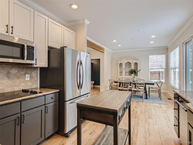 a kitchen with stainless steel appliances a stove a refrigerator a sink a dining table and chairs