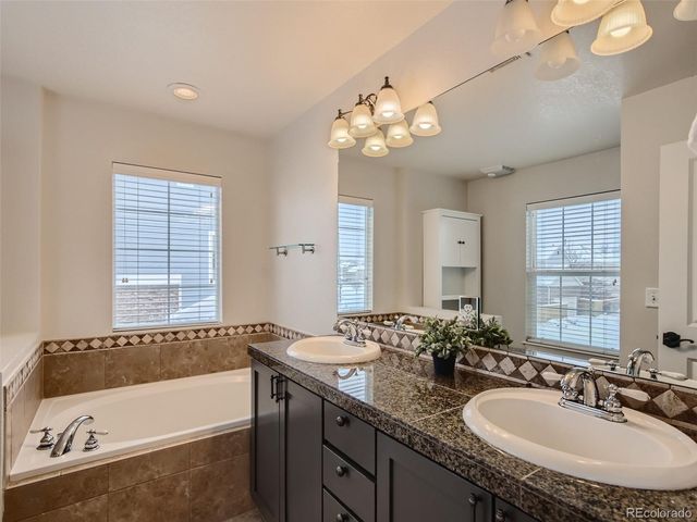 a bathroom with a granite countertop bathtub a sink and a large mirror