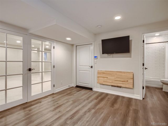 an empty room with wooden floor cabinet and windows