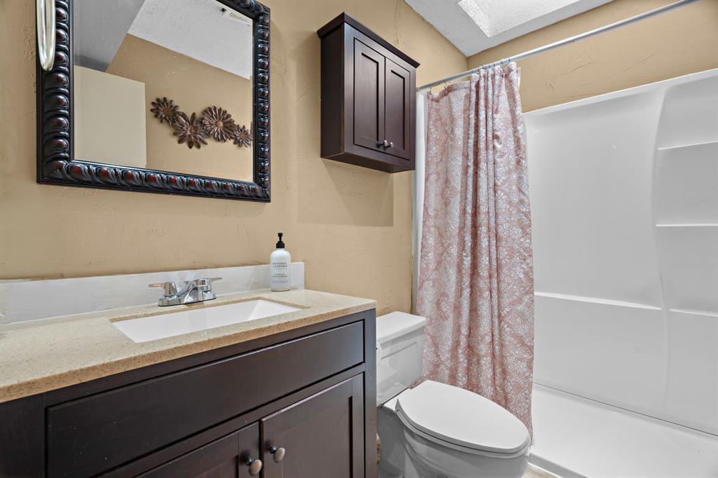 5107 Racquet Club Drive Arlington, TX 76017 - Photo 23 of 40 a bathroom with a sink a toilet and shower curtain