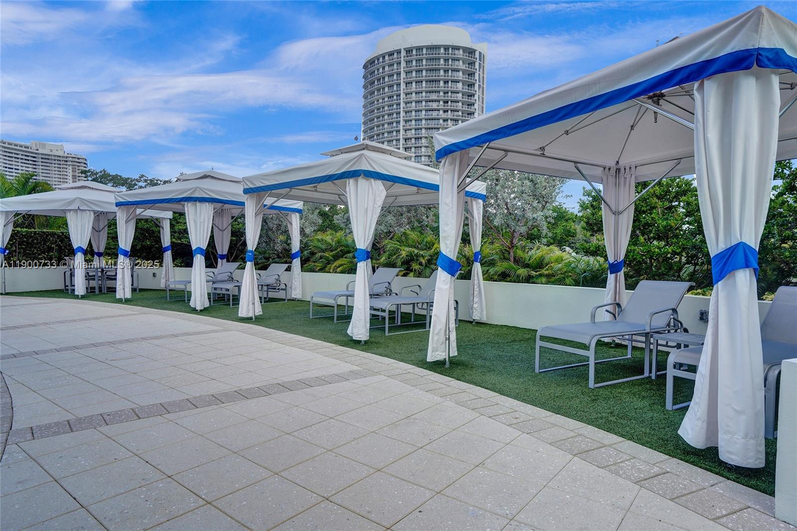 3000 Island Boulevard, Unit 1106 Aventura, FL 33160 - Photo 68 of 71 a view of a patio with table and chairs and a yard