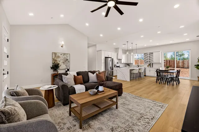 a kitchen with stainless steel appliances granite countertop a refrigerator a stove a sink a dining table and chairs with wooden floor