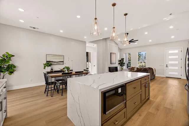 a view of a dining room and livingroom with furniture wooden floor kitchen view