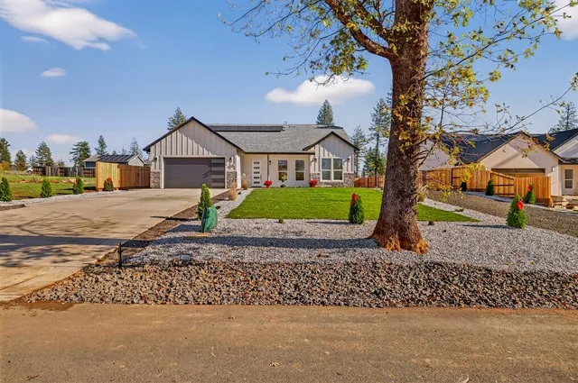 a view of a house with a yard and large tree