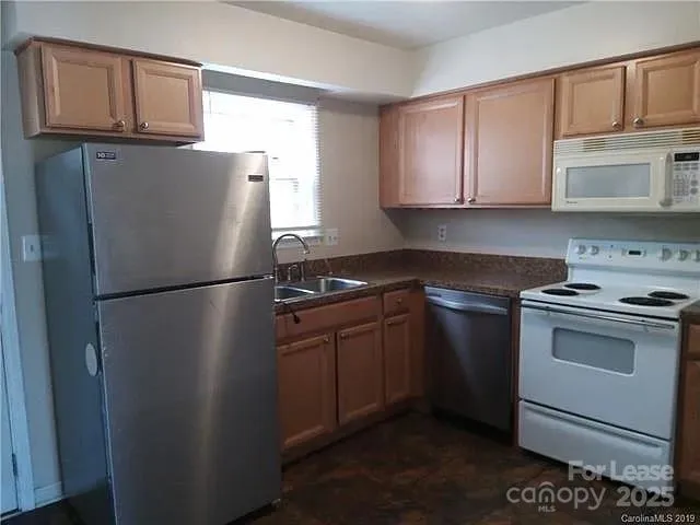 a kitchen with stainless steel appliances granite countertop a refrigerator a stove a sink and a microwave