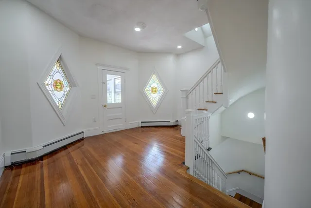 a view of empty room with wooden floor and window