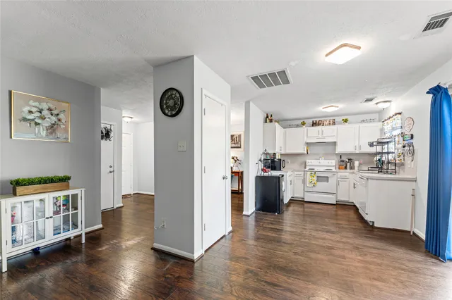 a kitchen with stainless steel appliances granite countertop a refrigerator a stove a sink dishwasher and white cabinets with wooden floor