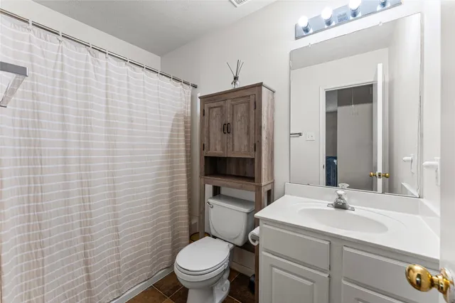 a bathroom with a granite countertop toilet sink and mirror