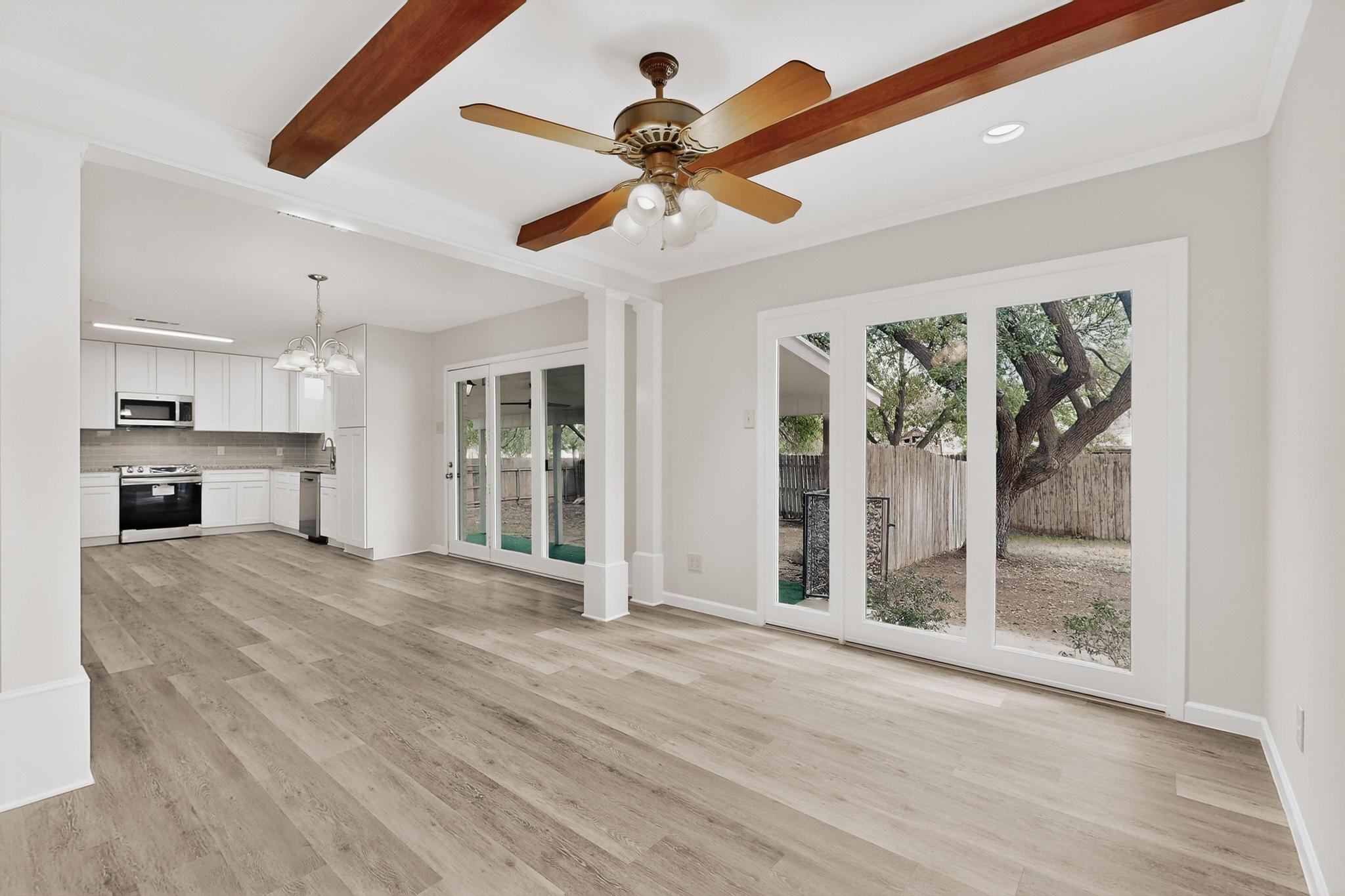 812 George Street Taylor, TX 76574 - Photo 6 of 34 Unfurnished living room with hanging lights, ceiling fan, light wood-style floors, and beamed ceiling