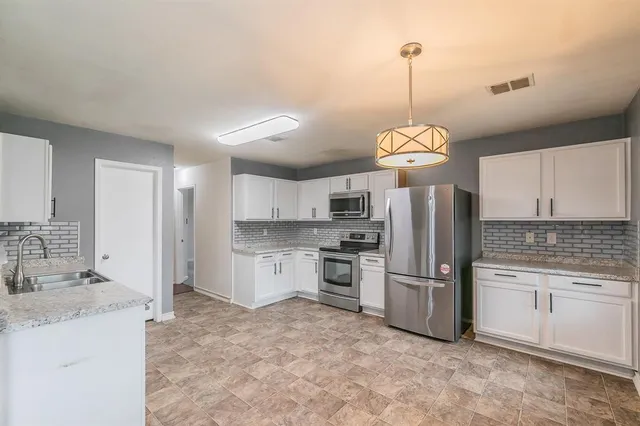 a kitchen with stainless steel appliances granite countertop a sink a stove a refrigerator cabinets and a window