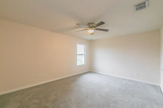 an empty room with a window and a fan