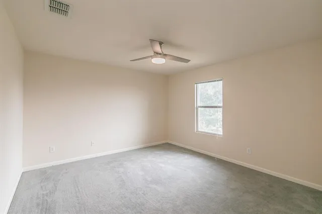 an empty room with a window and a ceiling fan