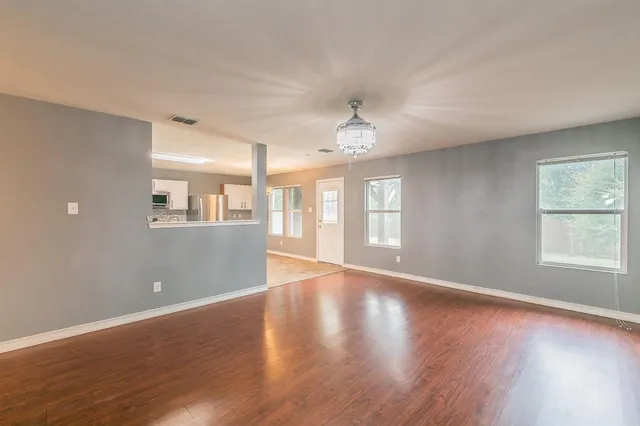 a view of an empty room with wooden floor and a window