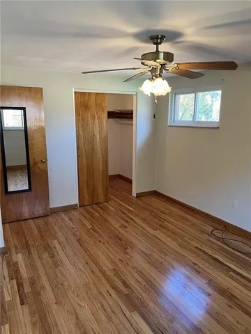 a view of a livingroom with wooden floor a ceiling fan and a window