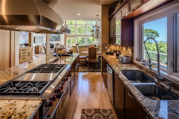 a kitchen with stainless steel appliances granite countertop a stove top oven a dining table and chairs with wooden floor