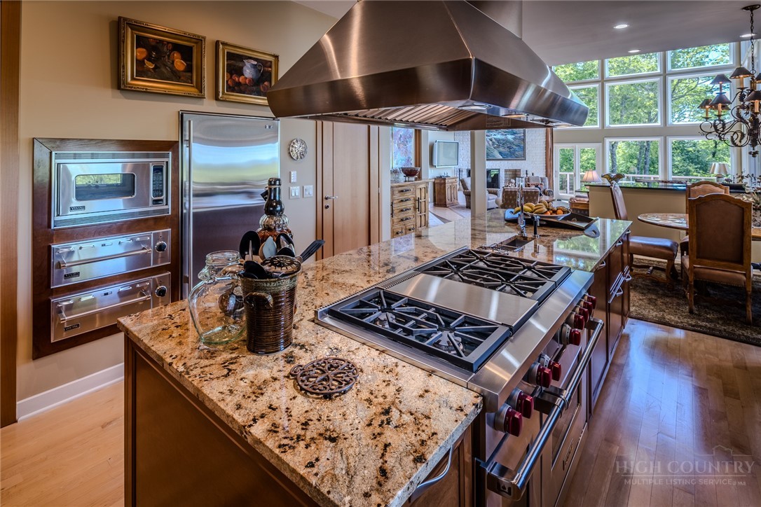 331 Branch Water Run Linville, NC 28646 - Photo 19 of 50 a kitchen with stainless steel appliances granite countertop a stove top oven a dining table and chairs with wooden floor