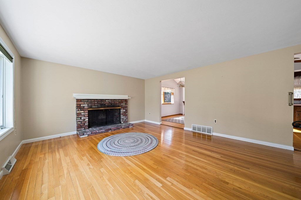 61 Orchard Road Marshfield, MA 02050 - Photo 3 of 33 an empty room with wooden floor fireplace and windows