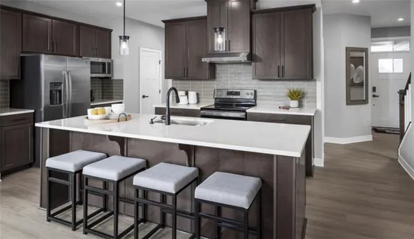 a kitchen with stainless steel appliances a table chairs refrigerator and wooden cabinets