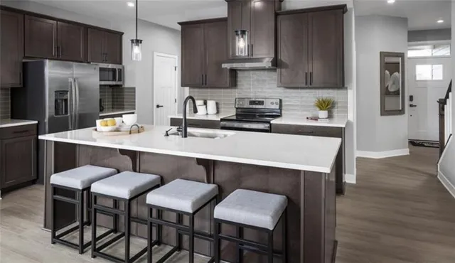 a kitchen with stainless steel appliances a table chairs refrigerator and wooden cabinets