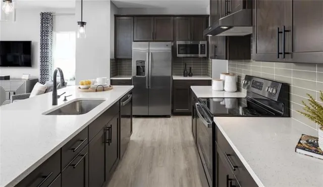 a kitchen with stainless steel appliances granite countertop a sink a stove and a refrigerator